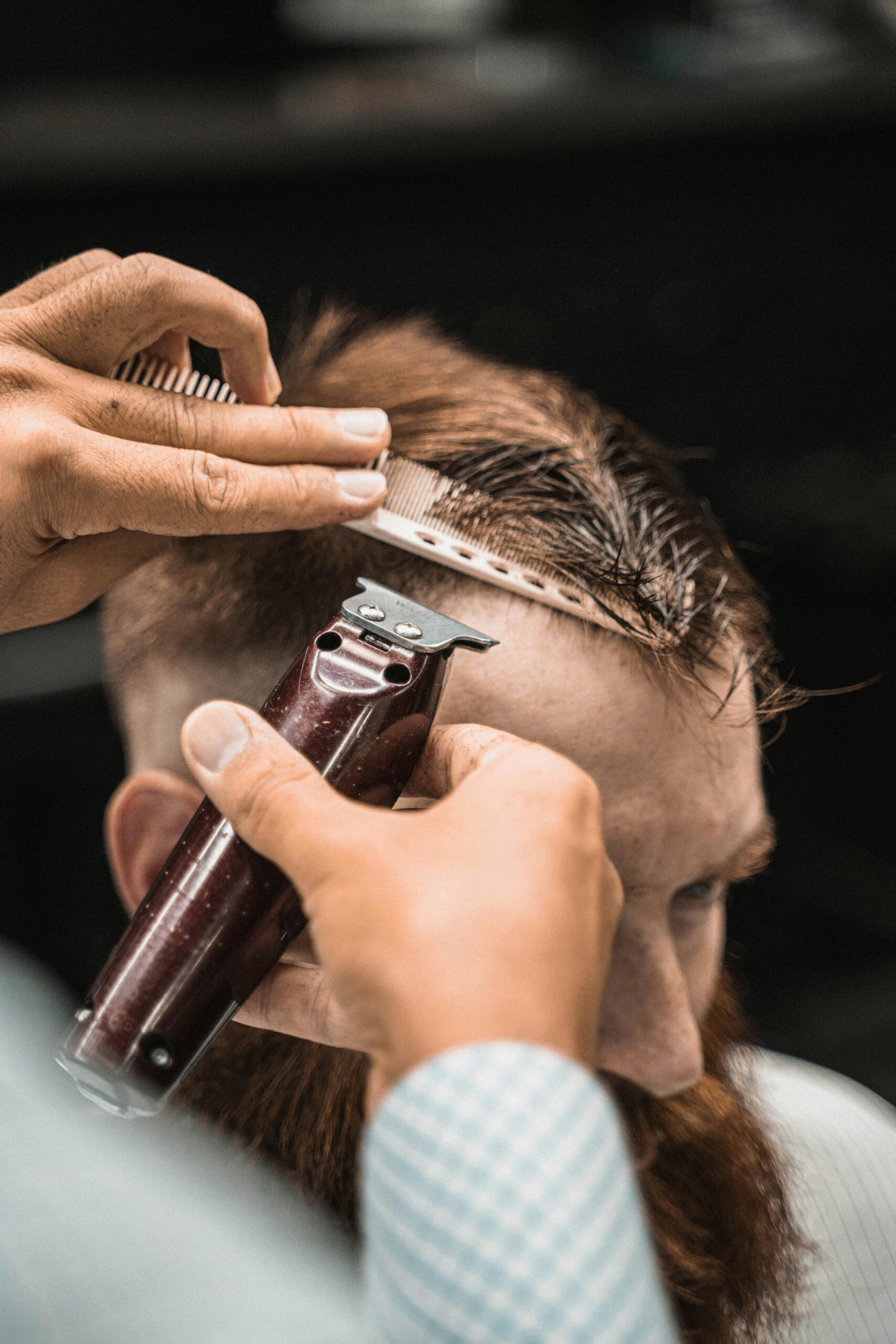 Close-up of a barber using clippers to cut a man